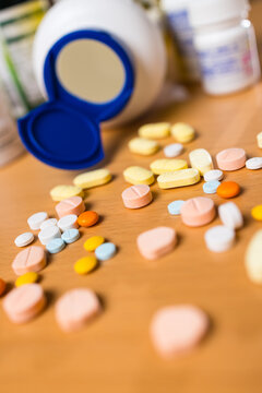 Many colorful pill and tablet on a wooden table near bottle cap
