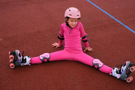 Girl on roller skates practicing splits on a red surface at a skate area