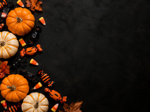 Halloween candy and pumpkins flat lay with dark copy space