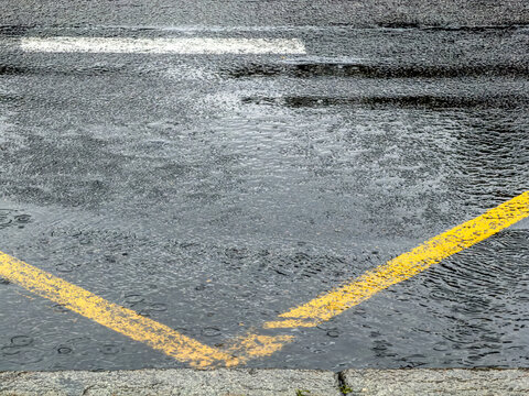 puddle and stream of rainwater with raindrops splashes on the asphalt road.
