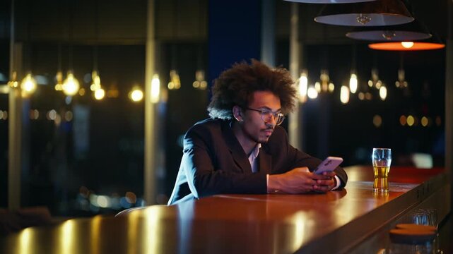 Man texting phone bar counter night. Business man waiting beer glass evening.