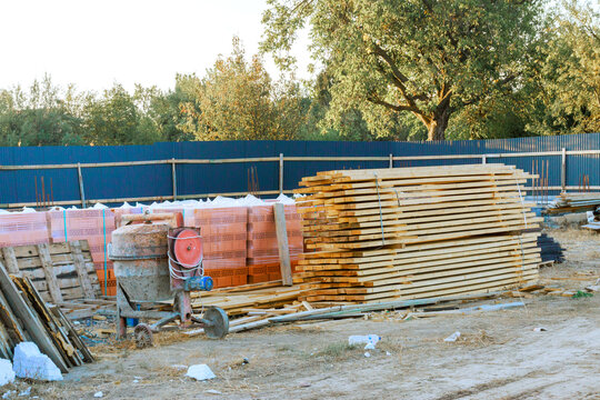 Wood planks, pallets are stacked at construction site with materials used for building.