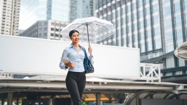 Business asian woman holding an umbrella walking to work under rain lifestyle in southeast asian on rainy season