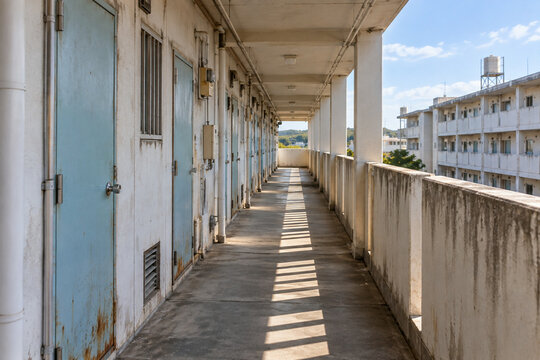 Open-air corridor of an old Japanese public housing apartment block, weathered steel doors receding in perspective