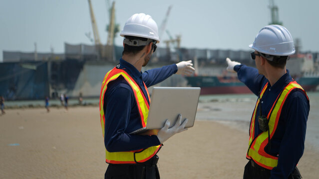 Engineers in safety gear walk beside the water at a port inspected the operations of the deep-sea port
