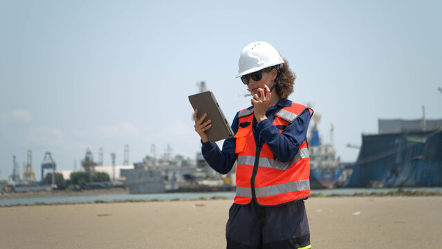 Female engineers in safety gear walk beside the water at a port inspected the operations of the deep-sea port