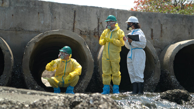 Environmental response team in hazmat suits collecting wastewater samples