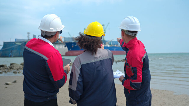 Port engineering team collaborating near cargo vessel and industrial shipping terminal