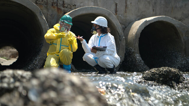 Environmental engineers in hazmat suits collecting contaminated water samples
