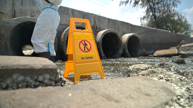 Warning sign and hazardous work area near polluted wastewater drainage tunnel