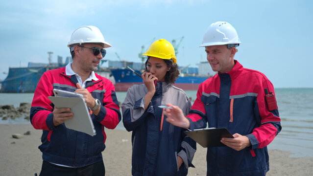 Port engineering team collaborating near cargo vessel and industrial shipping terminal