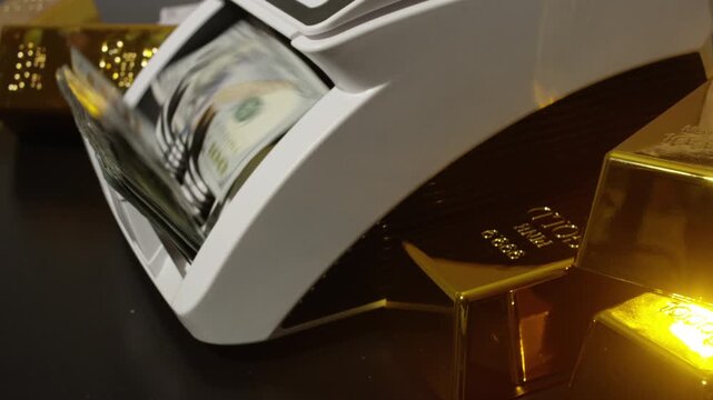 Money counting equipment. Bank financial operations. Counting machine counting dollar bills. Money counter counting dollar bills. Gold bar and 100 dollar banknotes. Finance and cash dollars concept.