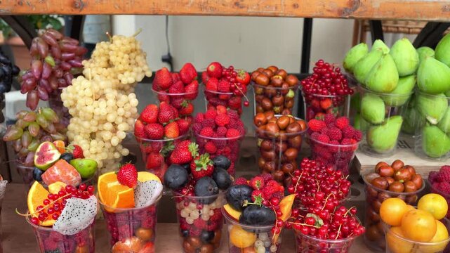 Assorted fresh fruit cups with berries and grapes arranged on a wooden table for catering events