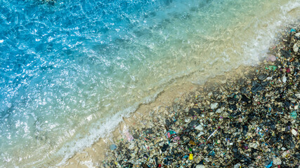 Top view of a beautiful turquoise beach polluted with a large pile of plastic waste and garbage  concept of ocean pollution, environmental crisis, and the impact on marine ecosystems.  © Media 