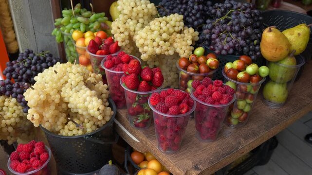 Assorted fresh fruit cups with berries and grapes arranged on a wooden table for catering events