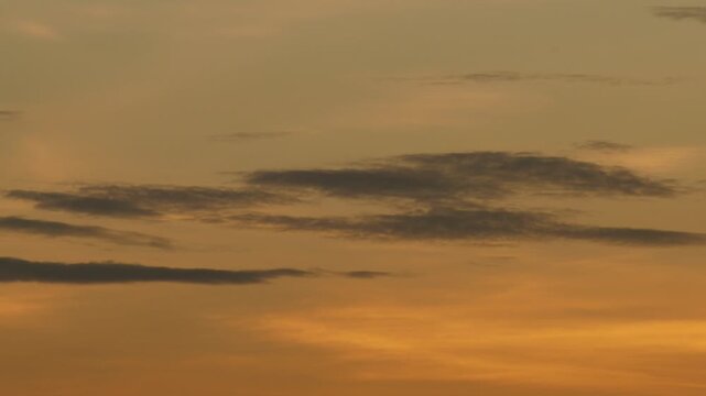 Silhouetted Clouds Against Bold Orange Sunset Gradient Sky