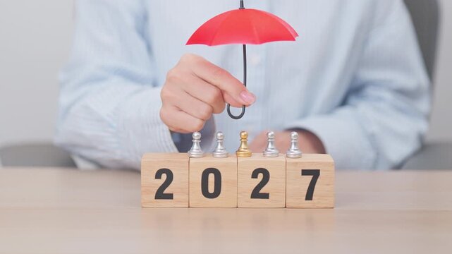 Happy New Year 2027 with hand holding red umbrella. Insurance, protection, safety and New year holiday Concepts