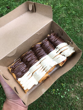 Crispy Indonesian pisang aroma banana spring rolls topped with melted chocolate and white vanilla glaze in a cardboard takeaway box