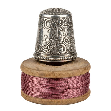 Silver thimble resting on wooden spool with pink thread on transparent background