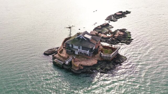 Island home. Castaway house alone on quiet island. Solitary island house. Getaway house on rocky island. Castaway style house in ocean.