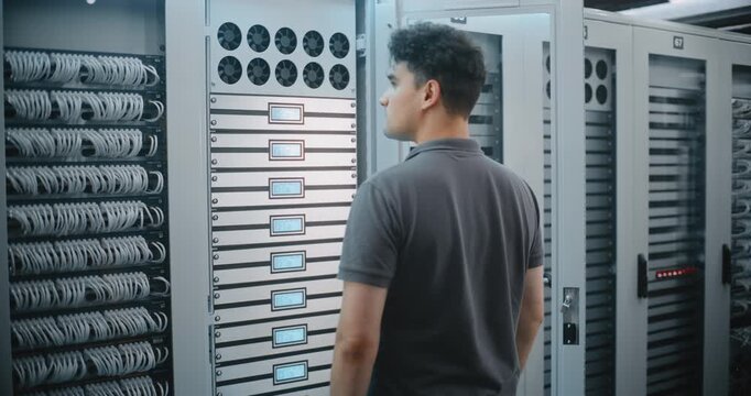 IT Technician Operates Illuminated Controls on Server Cabinet, Checking Equipment Indicators During Hands-on Maintenance Work in Professional Data Center Environment Supporting Digital Infrastructure.