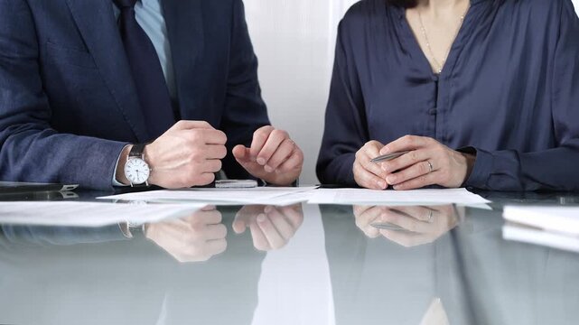 Business partners or lawyers are reviewing contract terms during a meeting, negotiating and making decisions together. Business people concept, close up view