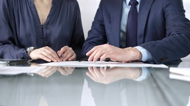 Business partners or lawyers are discussing contract papers during a meeting, negotiating and making decisions together. Business people concept, close up