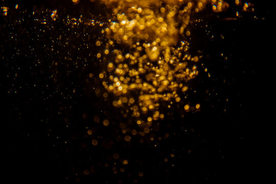 Abstract blurred golden bokeh lights against a dark background, creating a dramatic and festive atmosphere with glowing and shimmering effects, perfect for holiday and celebration themes.