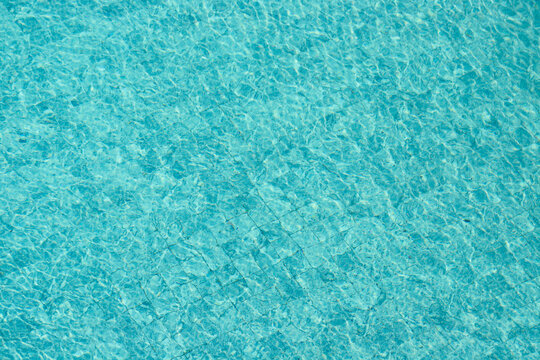 Vibrant blue water surface with shimmering reflections and ripples under sunlight