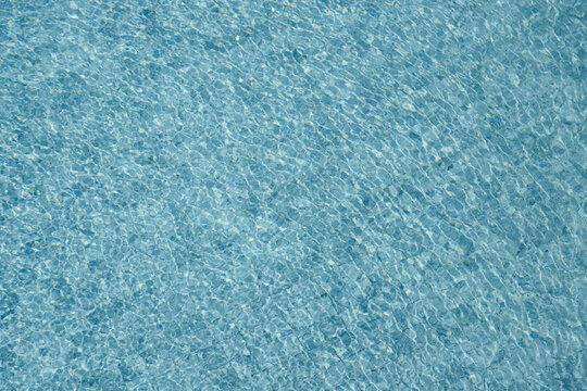 Vibrant blue water surface with shimmering reflections and ripples under sunlight