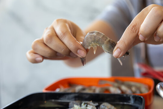 close-up shot of hands carefully preparing fresh shrimp.