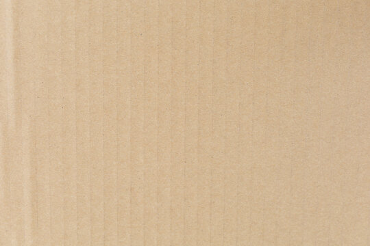 Close-up of textured beige corrugated cardboard surface, showcasing vertical ridges and subtle shading.