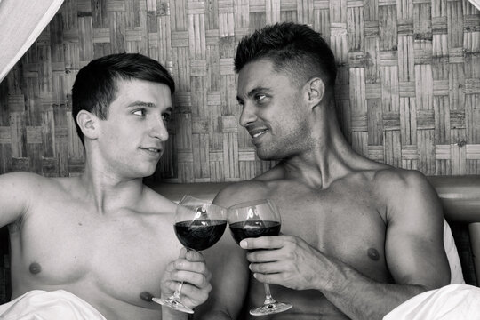 Young sweet couple have same-sex romance, embracing in bed kissing, passionate active man catches his boyfriend, honeymoon,