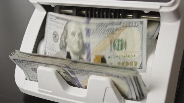 Hundred dollar bills moving through counting machine. Money counting processing. Hundred dollar notes in banking operation. American currency. Financial business success theme with dollar movement.
