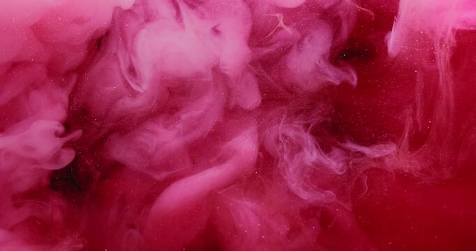 Fume ink. Underwater mist. Defocused pink red glitter color water pigment liquid particles cloud fluid spreading on abstract background.