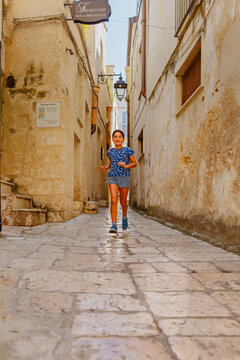 Young Girl Running Through Historic Stone Alley in Altamura, Apulia, Italy