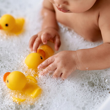 Exploring bubbles and playful ducks: baby hands in a joyful bath time moment Generative AI