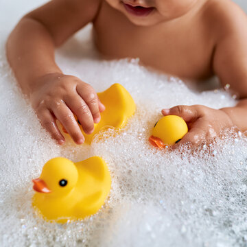 Tiny hands explore the joy of bath time with playful rubber ducks amidst fluffy bubbles Generative AI