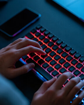 Hands typing on a colorful keyboard, illuminated by soft backlight during a late-night session Generative AI