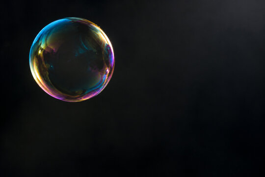Iridescent soap bubble floating on dark background