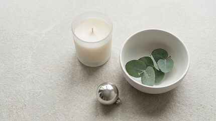 Frosted glass candle and eucalyptus leaves on a textured surface © ador 