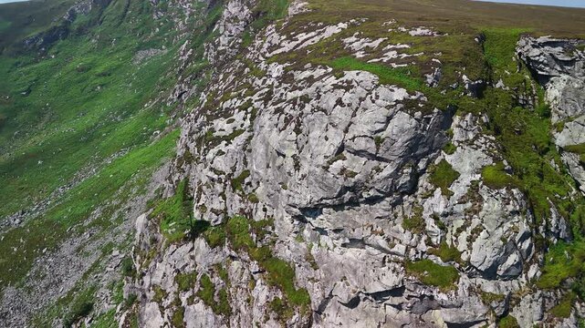 Aerial turn around the cliffs of Lough Tay revealing the surrounding landscape