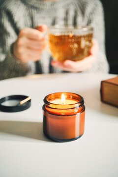 Woman enjoying warm tea and candlelight during cozy evening at home