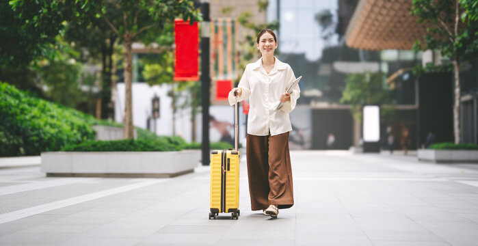 Young adult business asian woman happy walking with travel luggage and shopping bags