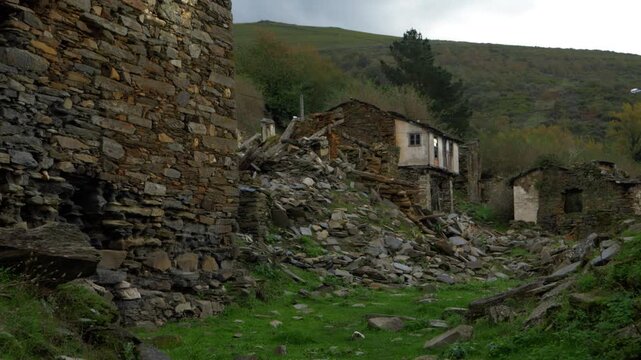 View of abandoned stone houses and rural ruins in Santoalla do Monte, Galicia, Spain, surrounded by vegetation in the remote mountain settlement affected by depopulation