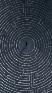 Top down view of a lone person standing in the center of a maze
