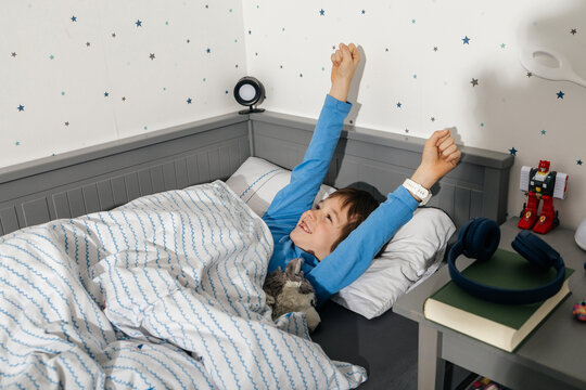 Young boy waking up stretching happy in bed