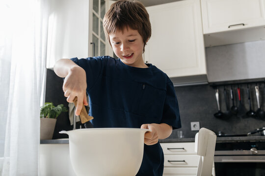 Young boy learning cooking skills in home kitchen