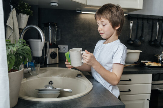 Young boy washing dishes in kitchen showing responsibility