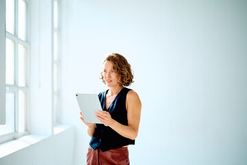 Young businesswoman working on a portable device, managing tasks and communicating in a modern, minimalistic workspace © we.bond.creations